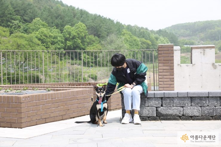 동물보호소는 위기에 처한 동물들에게 매우 중요한 곳이다.. 한 사람이 강아지와 함께 앉아있는 사진