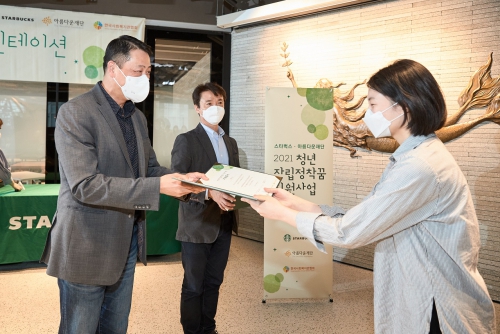 청년자립정착꿈 지원사업에서 스타벅스 송호섭 대표이사가 아름다운재단 권찬 사무총장과 함께 지원자에게 지원증서를 수여하고 있다