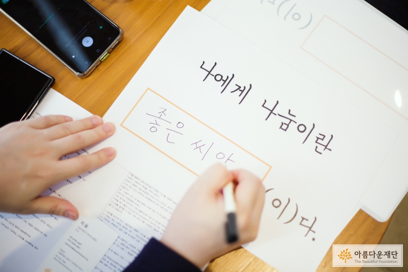 정경찬 기부자가 "나에게 나눔이란 000이다"로 적힌 흰 종이에 글을 쓰고 있다. 정경찬 기부자는 나에게 나눔이란 좋은 씨앗이라고 썼다. 