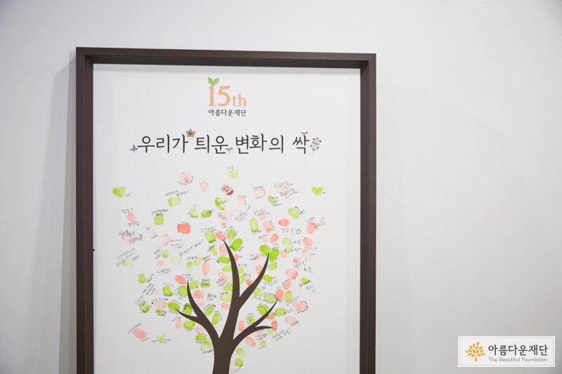액자가 하나 있고, 안의 그림은 나무한그루가 있으며 사람들이 지문으로 찍은 새싹 모양들이 돋아나 있는 형상입니다.