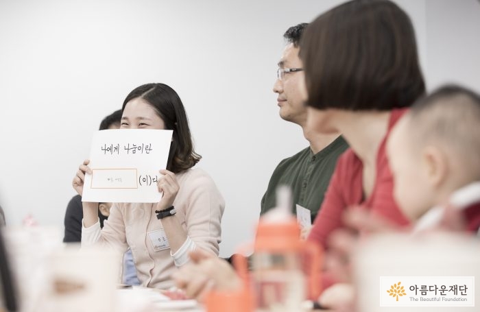 나에게 나눔이란 - 자신의 마음을 담아 나눔을 표현한 기부자가 발게 웃고 있다