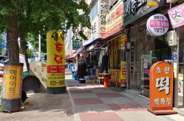 남원 구도심 전경. 마트, 교회, 부동산 등이 있는 작은 거리에 남원 촌닭, 초원떡백화점, 세종헤어아트 입간판에 세워져 있다.
