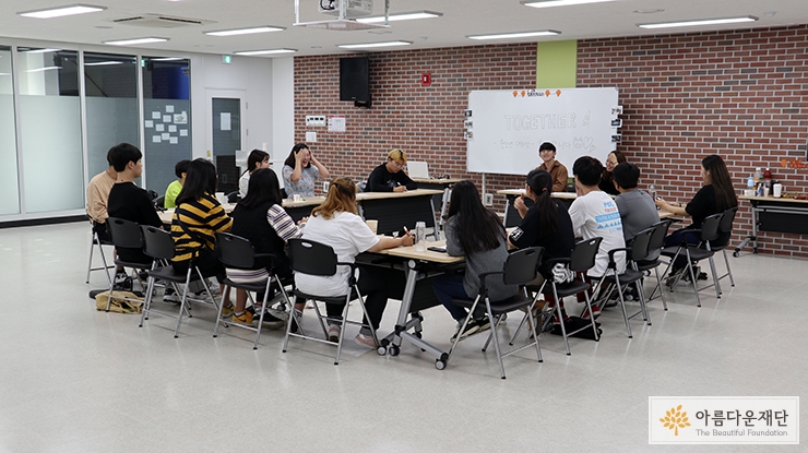 책상에 둘러앉아 이야기를 나누는 십여 명의 청소년들 모습