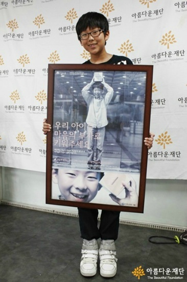 2010년 아름다운재단 창립 10주년 행사에 참석해 자신이 모델로 한 포스터를 들고 있는 재서 군